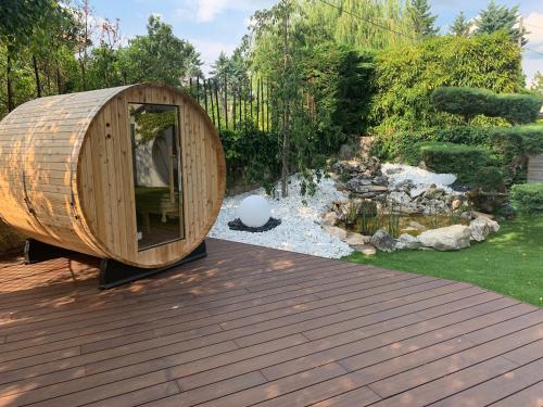 a circular wooden sauna on a deck next to a pond at Pont du Chalon Hôtel and Restaurant in Margès