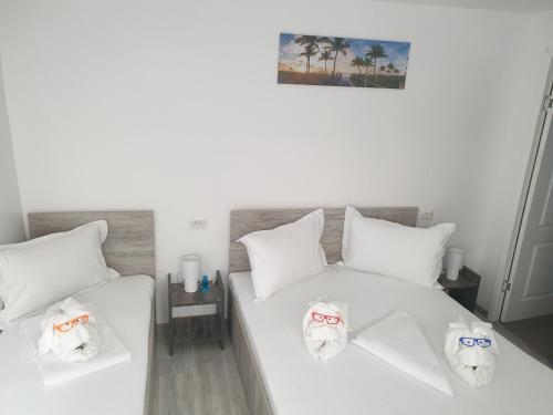 a bedroom with two white beds with towels on them at Casa David in Constanţa
