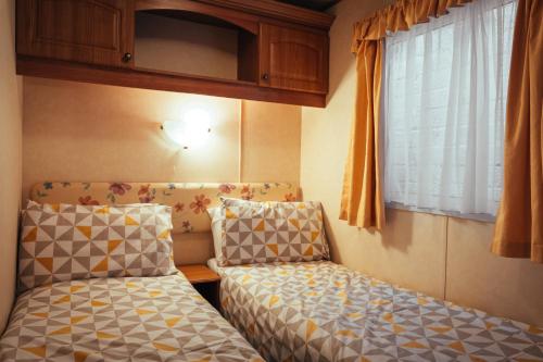 a small room with two beds and a window at Aaranmore Mobile Home in Portrush