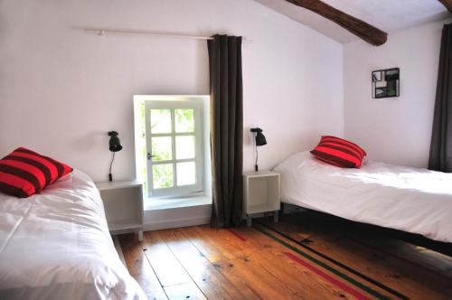- une chambre avec 2 lits dotés d'oreillers rouges et d'une fenêtre dans l'établissement Orangerie de Cardet - Apartment L'Oranger, à Cardet