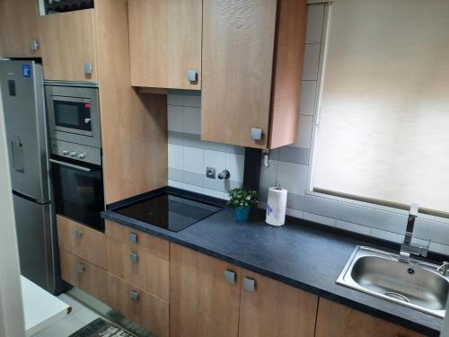 Una cocina con gabinetes de madera y una encimera negra. en estudio centro, en Logroño