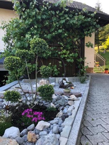 a garden with rocks and flowers in front of a building at SavaDolinka House in Mojstrana