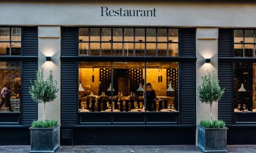 Una donna sta in piedi alla finestra di un ristorante di Radisson Blu Edwardian Mercer Street Hotel, London a Londra