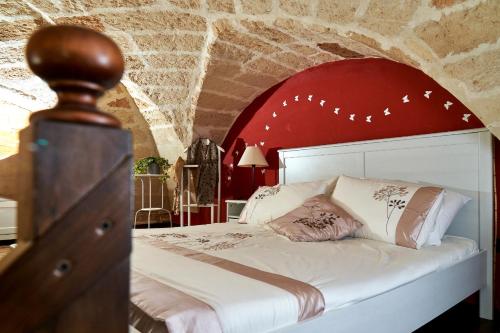 a bedroom with a white bed with a red wall at B&B Isola Dello Stampatore in Lecce
