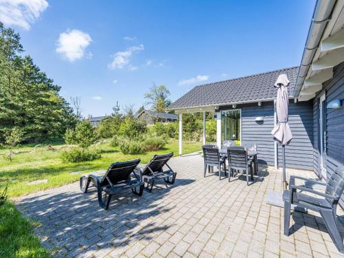 a patio with a bunch of chairs and an umbrella at 10 person holiday home in Nørre Nebel in Nørre Nebel
