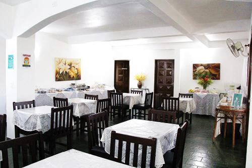 une salle à manger avec des tables, des chaises et un tissu de table blanc dans l'établissement Pousada Berro D'Água, à Cananéia