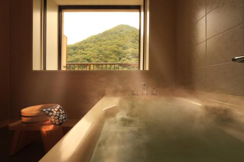 a bathroom with a bath tub with a window at Asaya in Nikko