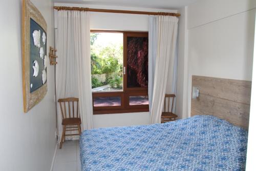 Un dormitorio con una cama azul y una ventana. en Apt na Praia do Forte em Condomínio frente mar!, en Praia do Forte