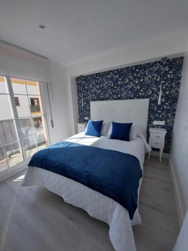 1 dormitorio con 1 cama grande con sábanas azules y ventana en Ático Chill Out la Biznaga en Málaga