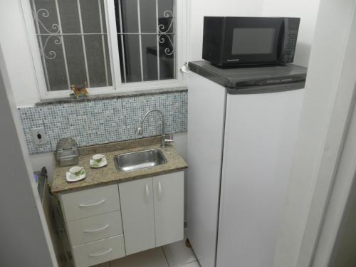 a small kitchen with a microwave on top of a refrigerator at Aconchego Valparaíso in Petrópolis