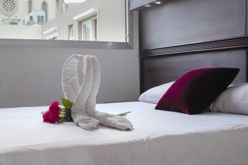 a pair of white socks and flowers on a bed at Hotel Le Paris in Noumea