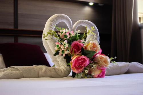 a bouquet of flowers and a towel on a bed at Hotel Le Paris in Noumea