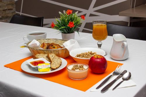 a table with a plate of breakfast food and an apple at Hotel Le Paris in Noumea