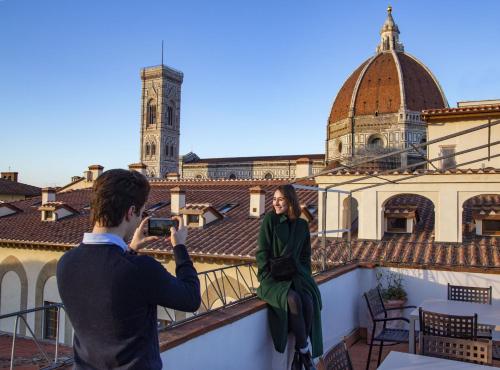 a man taking a picture of a woman on a balcony at Boutique Hotel del Corso in Florence