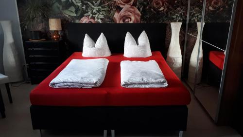 a red bed with four white pillows on it at Bauernhof Gästezimmer Hortus Sandrine Gemeinschaftsbad in Hausbreitenbach