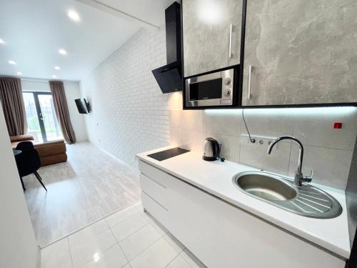 a white kitchen with a sink and a microwave at Апартаменты в Аркадии - Arcadia Sky Apartments in Odesa