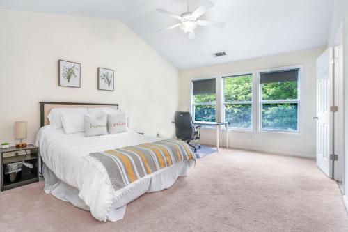 a bedroom with a bed and a desk and windows at Sunny and Modern Single House with Gym, 4 Bedrooms- 3min drive to I-85 Highway in Duluth