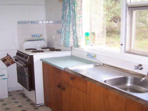 a kitchen with a stove and a sink and a window at 77 Gold Coast Drive in Carrickalinga