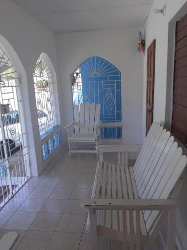 a porch with two white chairs and a blue door at Mack's Home in Clifton