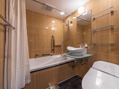 a bathroom with a sink and a tub and a toilet at APA Hotel Nishifunabashi Ekimae in Funabashi