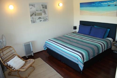 een kleine slaapkamer met een bed en een stoel bij The Beach Shack - OCEAN VIEWS, CLOSE TO THE BEACH in Guilderton