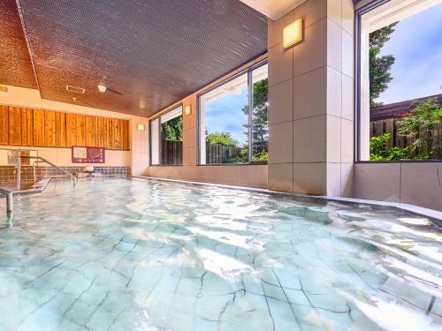 een binnenzwembad met een tegelvloer en ramen bij Yukai Resort Premium Shima Saichoraku in Shima