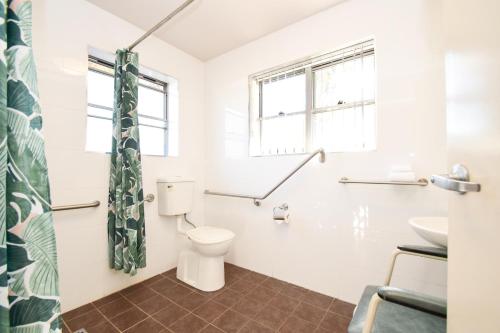 a bathroom with a toilet a sink and a window at Station Hotel Motel Kurri in Kurri Kurri