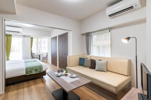 ein Schlafzimmer mit einem Bett, einem Sofa und einem Tisch in der Unterkunft BON Tokyo Asakusa in Tokio