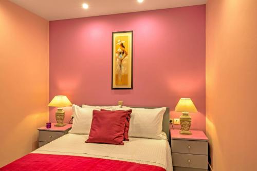 - une chambre aux murs roses et un lit avec deux lampes dans l'établissement cozy apartment-1, à Ayía Marína