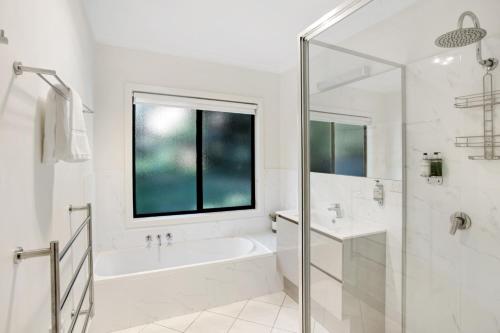 a white bathroom with a tub and a window at Tyntynder Garden Cottage 4 in Bright
