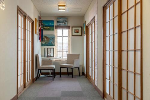 a hallway with two chairs and a table and windows at Guesthouse EN in Rusutsu