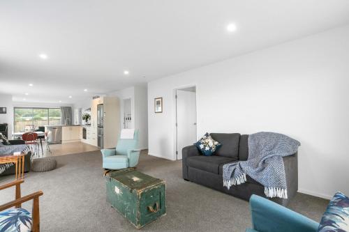 a living room with a couch and a chair at Karitane Beach Retreat - Karitane Holiday Home in Karitane