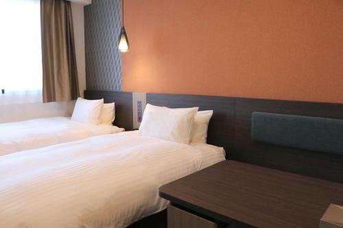 a hotel room with two beds and a table at Wander Kyoto Nanajo in Kyoto