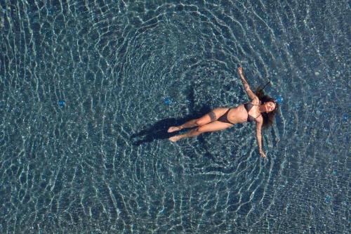 a woman in a bikini swimming in the water at Borgo dei Lecci Puglia in Selva di Fasano