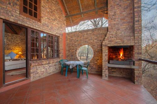 a brick patio with a table and a fireplace at SERENITY Du Bois Lodge in Marloth Park