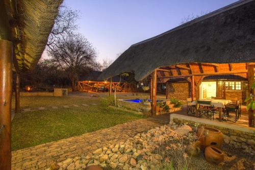 a house with a thatched roof and a patio at SERENITY Du Bois Lodge in Marloth Park