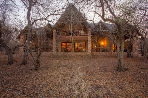 a large brick house with trees in front of it at SERENITY Du Bois Lodge in Marloth Park