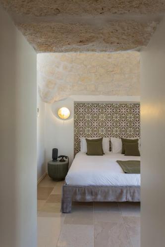 a bedroom with a large bed with a stone wall at Borgo dei Lecci Puglia in Selva di Fasano