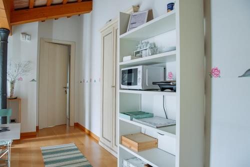 a room with white shelves with a microwave at Rosa del Grappa in Rosà