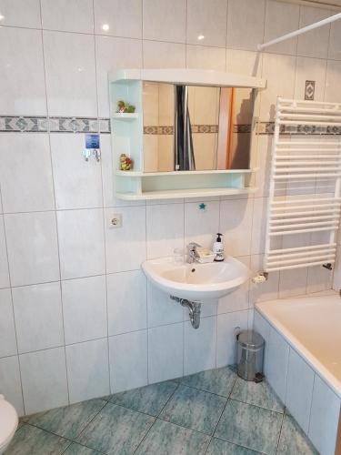 a bathroom with a sink and a mirror and a tub at Pension Zur Eiche in Drebenstedt