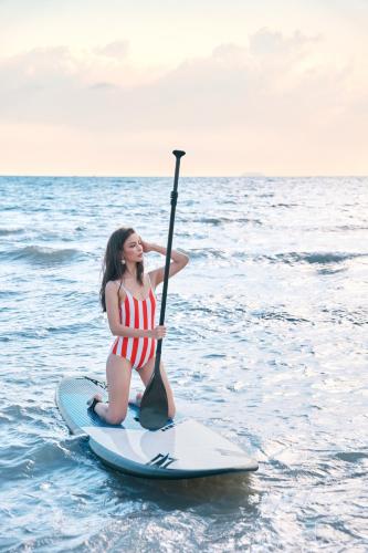 a woman in a bikini on a paddle board in the water at Bayphere Hotel Pattaya JC in Na Jomtien