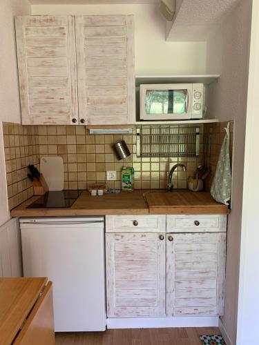 une cuisine avec des armoires blanches et un micro-ondes dans l'établissement Val de Llous I 40, à Sainte-Léocadie