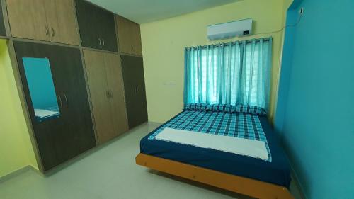 a bedroom with a bed and a window and cabinets at Tirupati Homestay - 2BHK AC Family Apartments near Alipiri and Kapilatheertham - Walk to A2B Veg Restaurant - Super fast WiFi - Android TV - 250 Jio Channels - Easy access to Tirumala in Tirupati