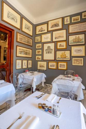 a dining room with white tables and pictures on the wall at The Rif - Boutique Hotel in Pisa