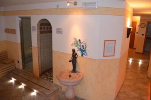 una estatua de una mujer sentada en un lavabo en el vestíbulo en Hotel Ladina, en Campitello di Fassa