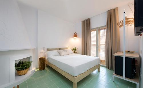 a bedroom with a white bed and a fireplace at Hostal Boutique Cana Rita in San Antonio