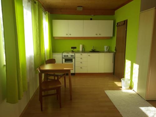 een keuken met groene muren en een tafel en stoelen bij Komfortzimmer Haus Dervaritz in Einöd