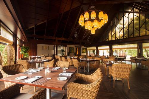 a restaurant with wooden tables and chairs and a chandelier at Sea Shell Samssara in Neil Island