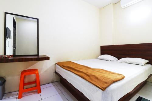 a bedroom with a bed with a mirror and a red stool at Guest House Taman Sari Syariah in Parit