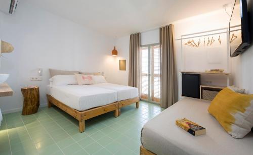 a bedroom with two beds and a television in it at Hostal Boutique Cana Rita in San Antonio
